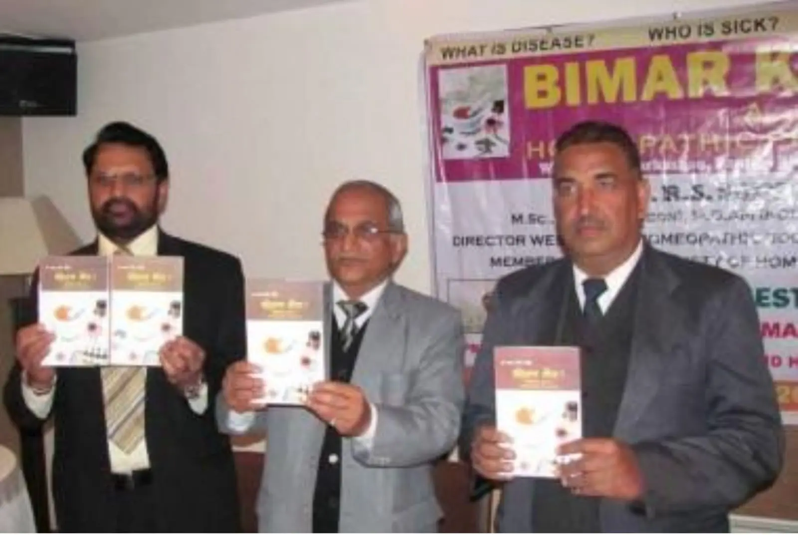 Dr. R. S. Saini and colleagues at the launch of Bimar Kaun?, each holding a copy of the book.